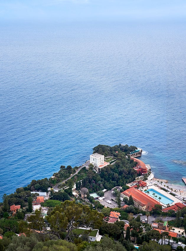 Panoramic view of the coast with houses and a pool by the sea.