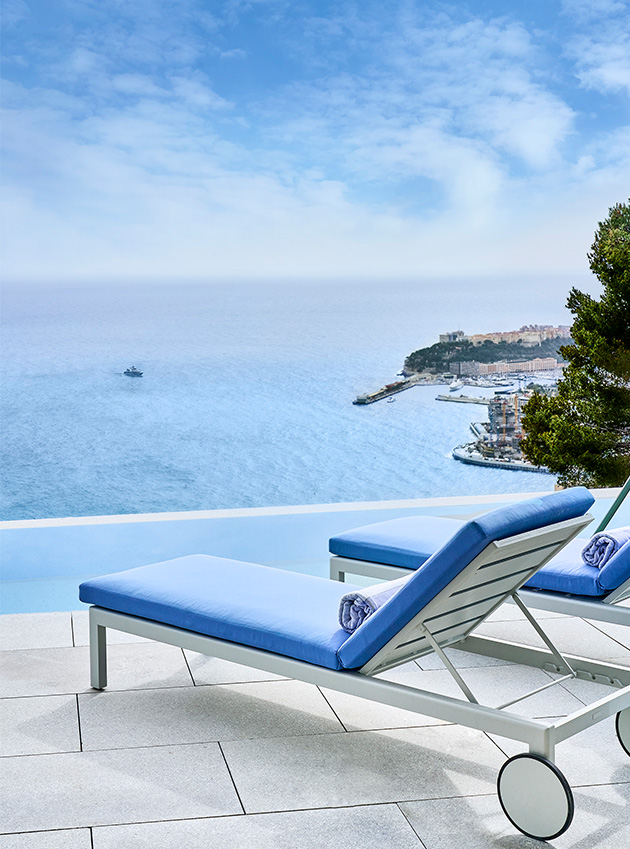 Two blue loungers in the infinity pool by the sea.