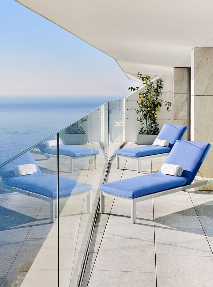 Two blue sun loungers on the terrace with a sea view.