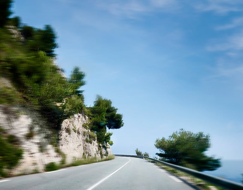 Close-up of the road next to the mountain and the sea.