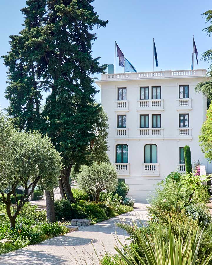 A path with trees around it leading to a white building.