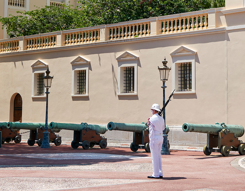 A man dressed in white next to some green cannons.