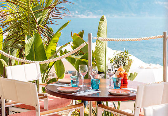 Brightly coloured food on a table with pink chairs around it at Maybourne La Plage beach club