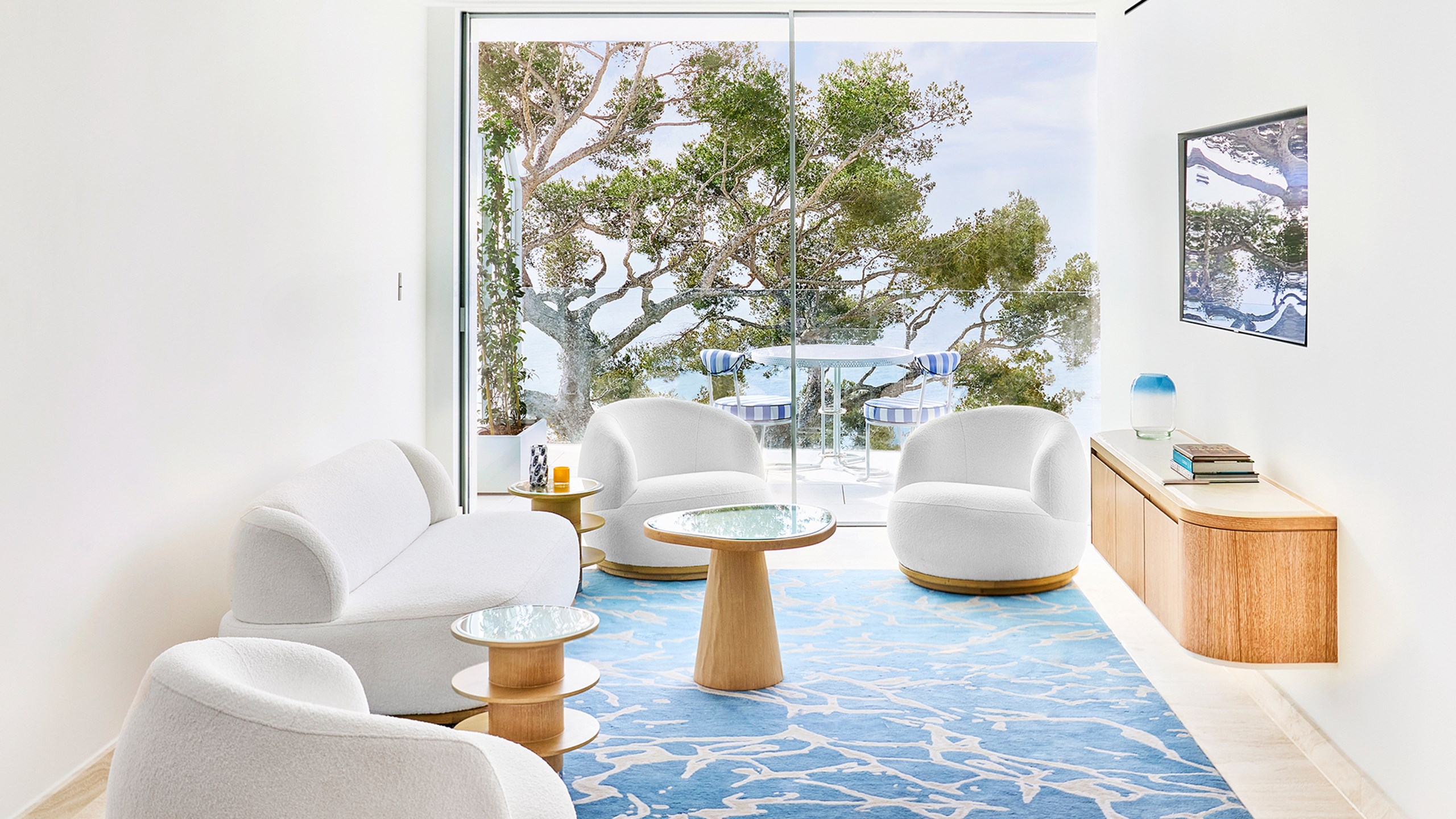 Un salon au Maybourne Riviera avec des fauteuils blancs et une terrasse avec table et chaises.