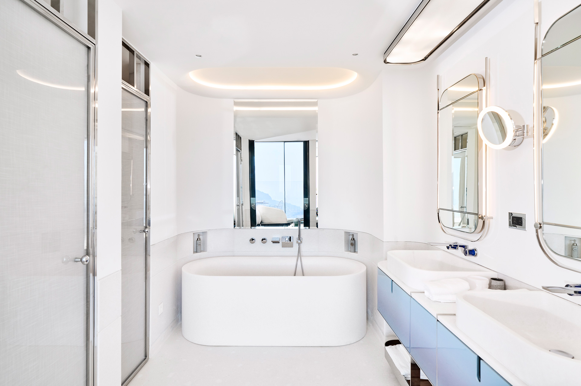 Deep white bathtub sits in the middle of the Panoramic Sea View Studio bathroom, lined with modern geometric mirrors