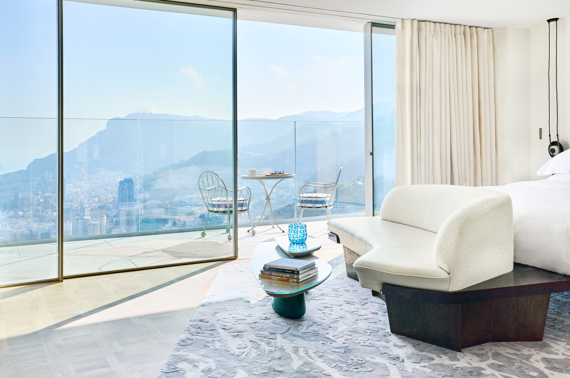 A white sofa at the end of the bed in a room with huge views of the sea.