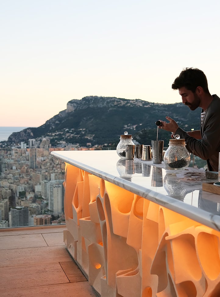Barman in Bar Ceto mixing cocktails against a dramatic backdrop of cliffs and the sea