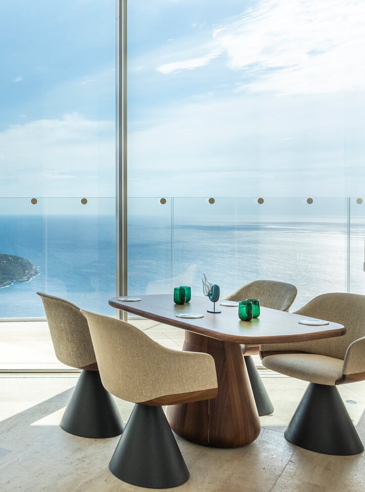 Wooden table with four chairs next to the window with sea view.