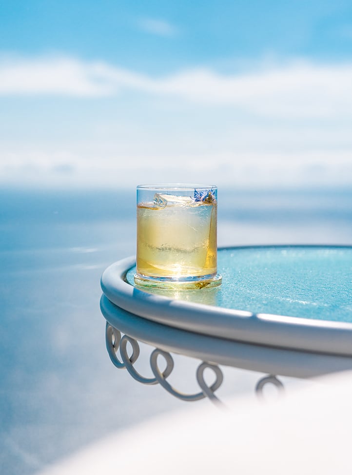 Short cocktail with lavender garnish in front of sea
