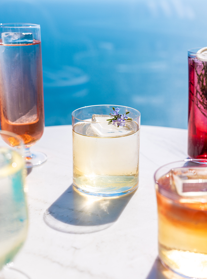 Cocktails de différentes couleurs sur une table avec le bleu de la mer en arrière -plan.