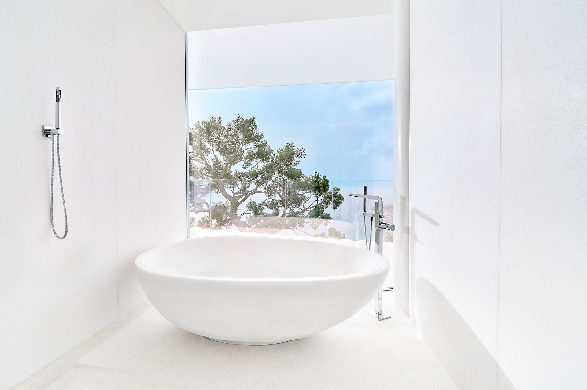 The large curved bathtub in the Sea View Suite overlooks the large tree in the hotel garden and the brilliant blue skies