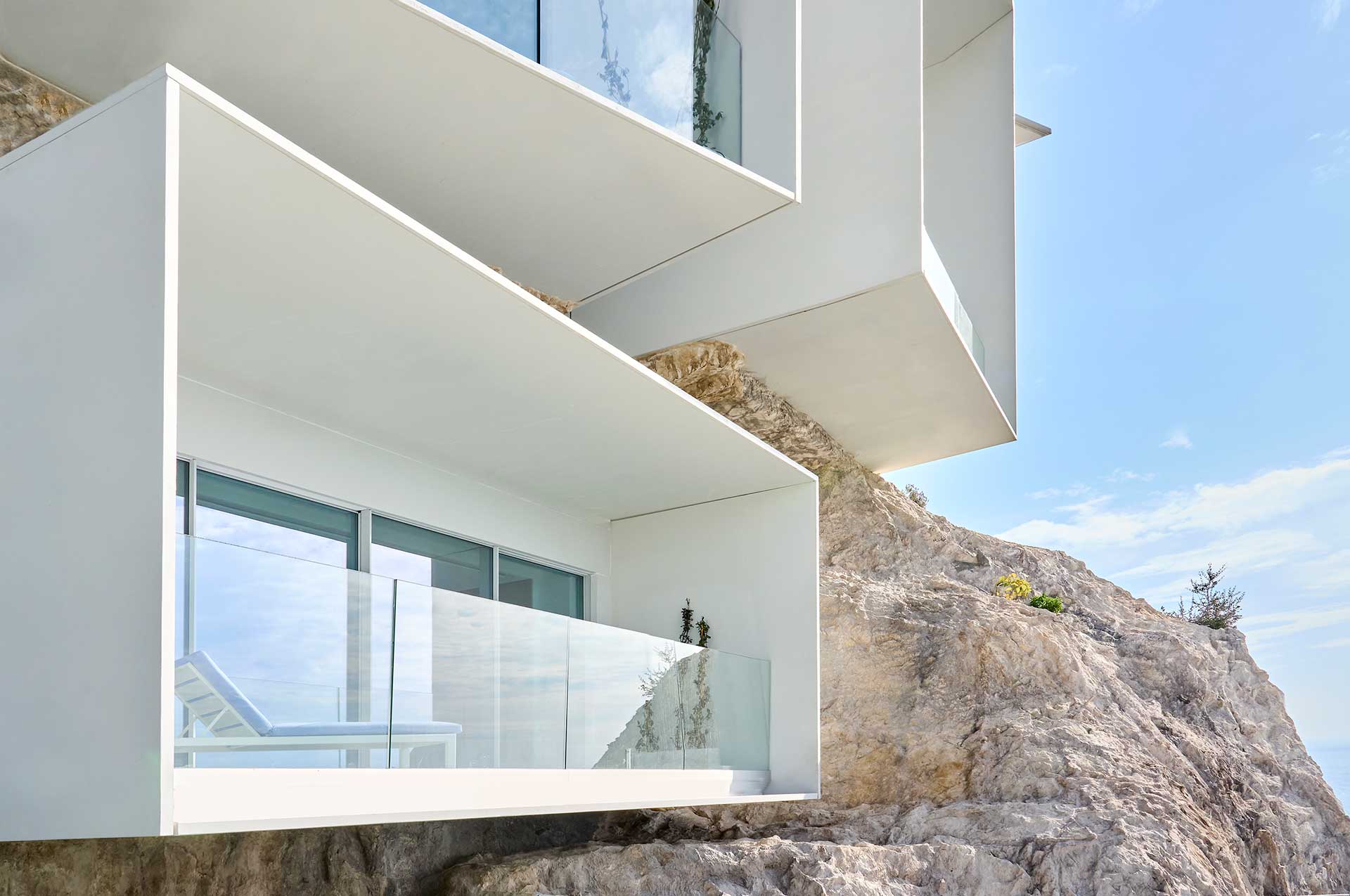 The modern geometric-style white balconies built into the dramatic cliff side