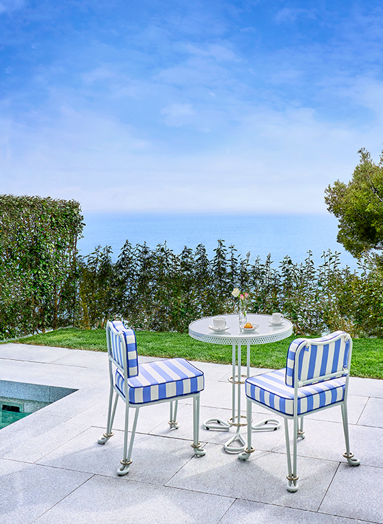 Table et chaises rayées bleu et blanc au bord de la piscine sur la terrasse de la Suite Corniche Duplex au Maybourne Riviera