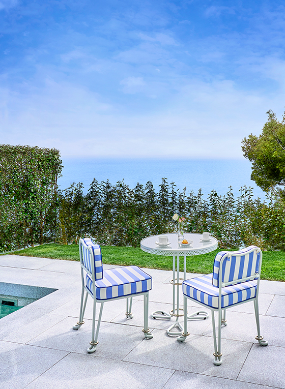 Table et chaises rayées bleu et blanc au bord de la piscine sur la terrasse de la Suite Corniche Duplex au Maybourne Riviera