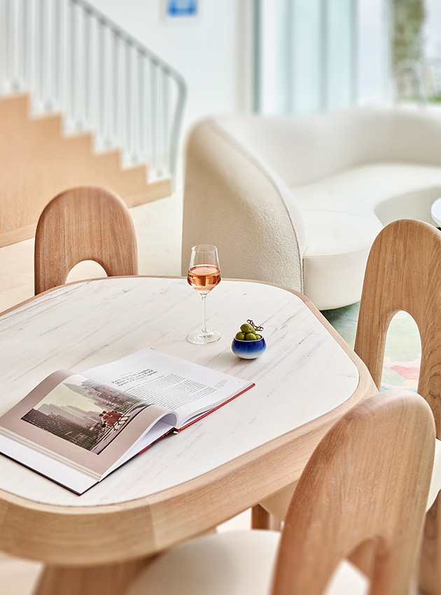 A glass of wine, olives and a magazine on a wooden table.