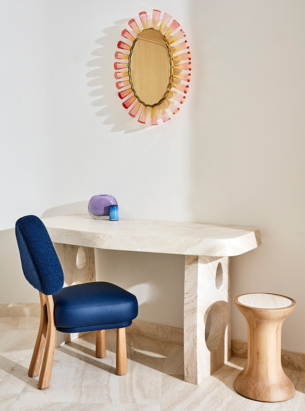 A desk with a blue chair and a sun-shaped mirror.