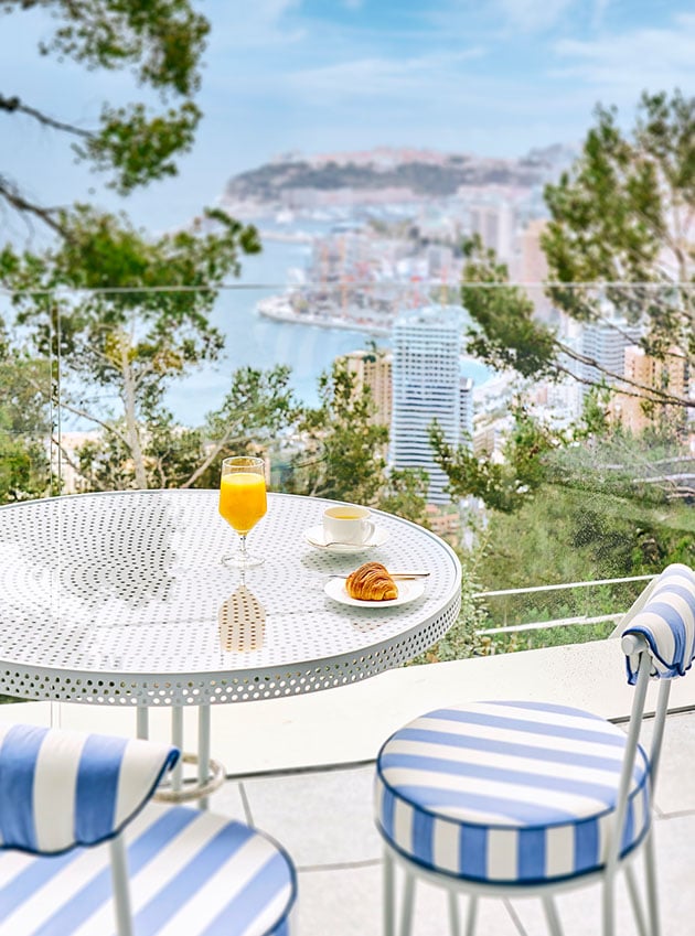 Two chairs and a breakfast table on the corniche Junior Suite terrace overlooking the coast.