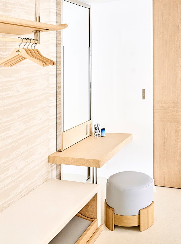 A wooden dressing table with a small armchair and a mirror.