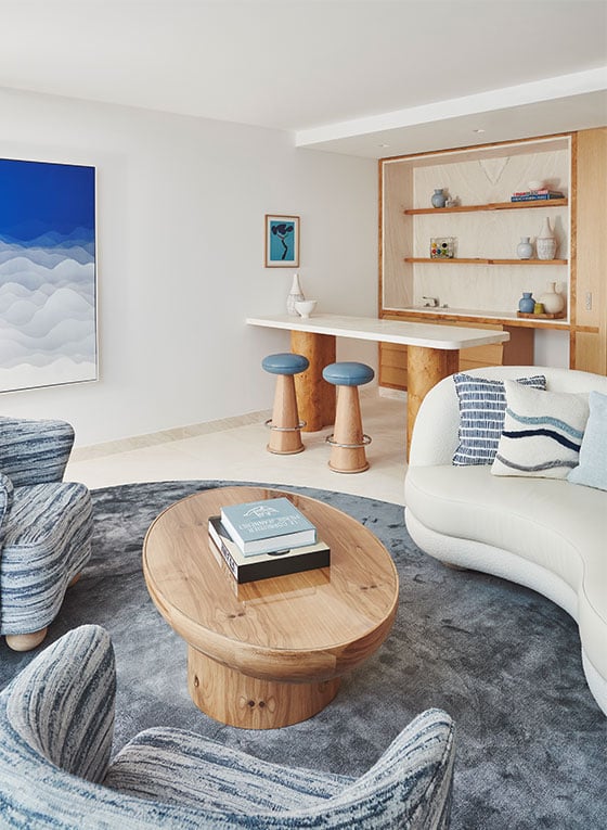 Living room of Grand Azur Suite with coffee table and three plush chairs around it, and bar in background