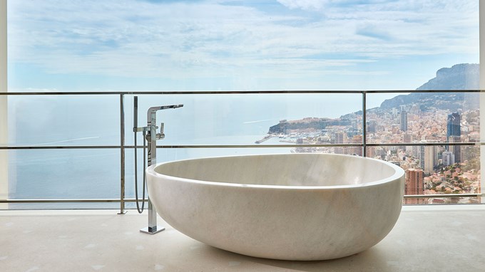 Round standalone bathtub sitting on balcony with sweeping sea views