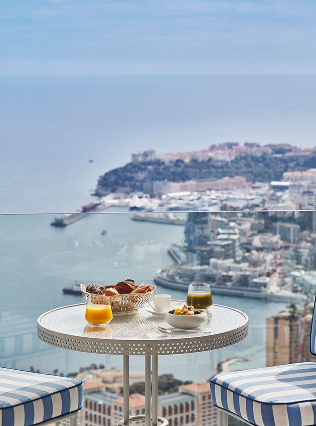 Juices and pastries served for breakfast on a gastro table on the balcony of the suite, looking out to the sea and Monaco