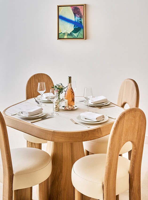 A wooden table with plates and glasses along with four chairs.