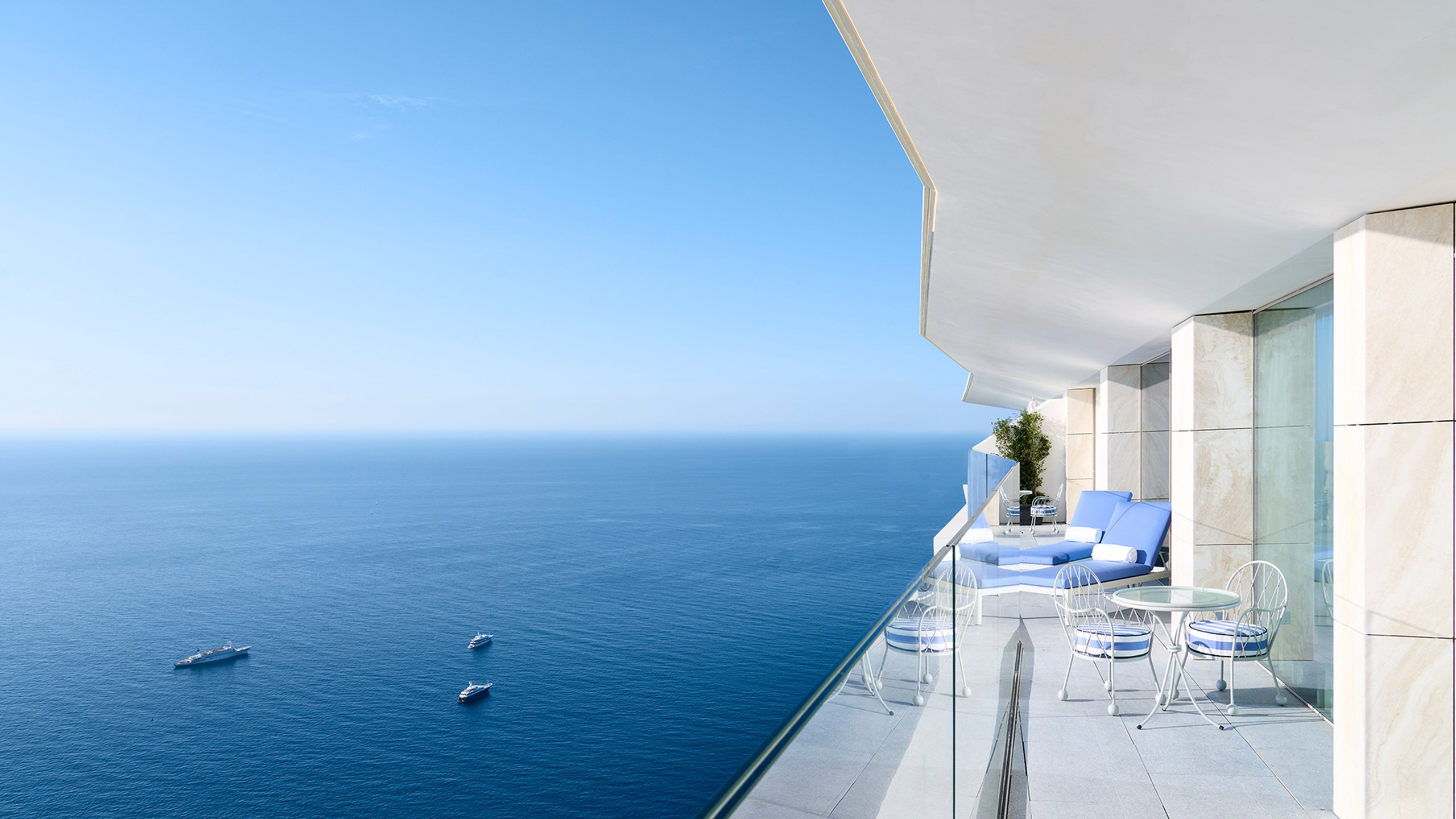 La terrasse de la Grande Suite Riviera avec deux transats bleus, une table et la vue sur la mer à l'infini