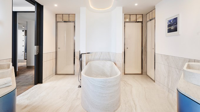 La salle de la bain de la Grande Suite Riviera avec une grande baignoire en marbre, et deux grandes portes en fond.