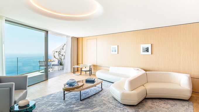 Grand Riviera Suite - salon avec canape, table basse et fenêtre du sol au plafond.