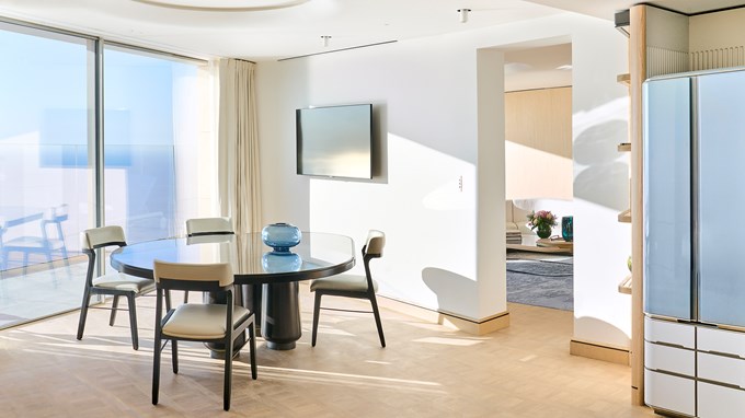 Grande Suite Riviera - salle à manger avec table à manger, TV et baie vitrée.
