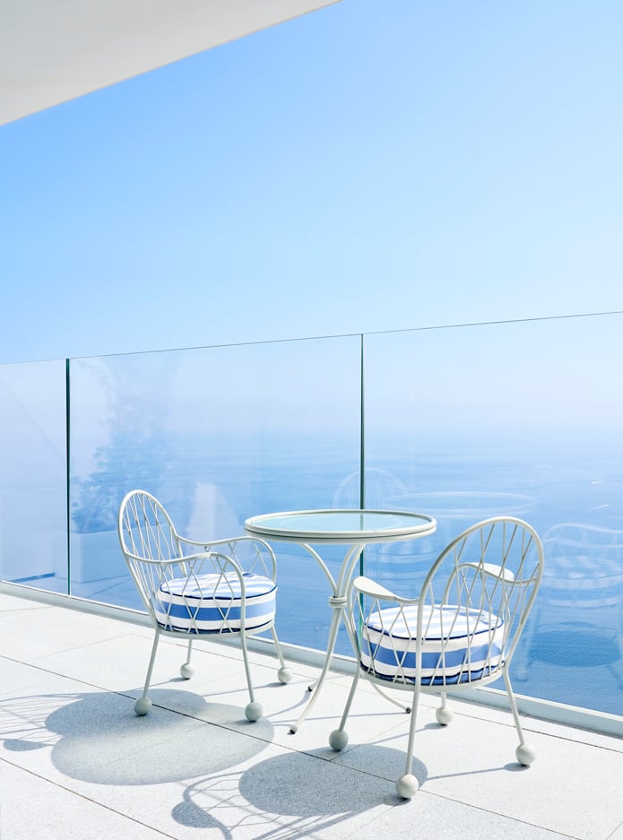 Two chairs and a round table on a terrace with a sea view.