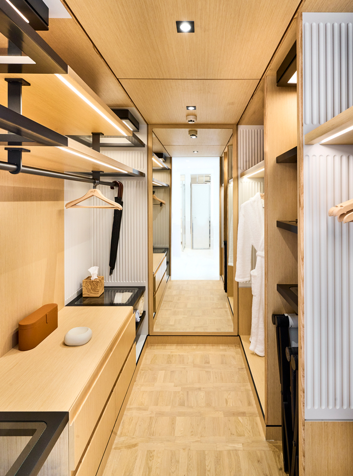 A spacious wooden walk-in closet with a white bathrobe.