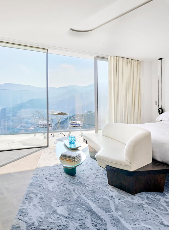 A white sofa at the end of the bed in a room with vast views of the sea.