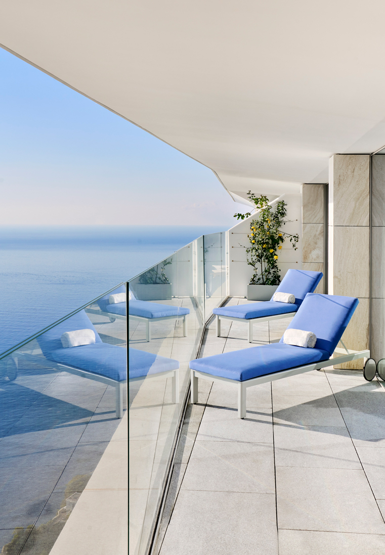 Two blue sun loungers on the terrace with a sea view.