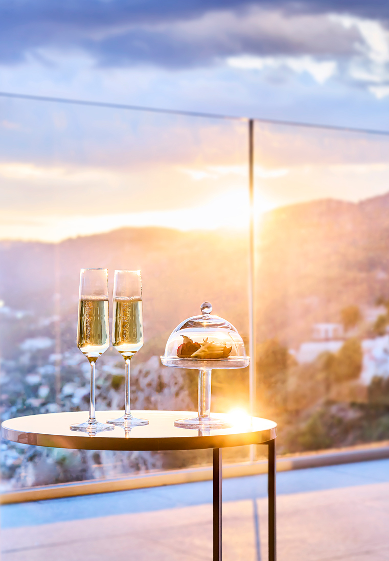 A table with two glasses of champagne on a terrace by sunset.