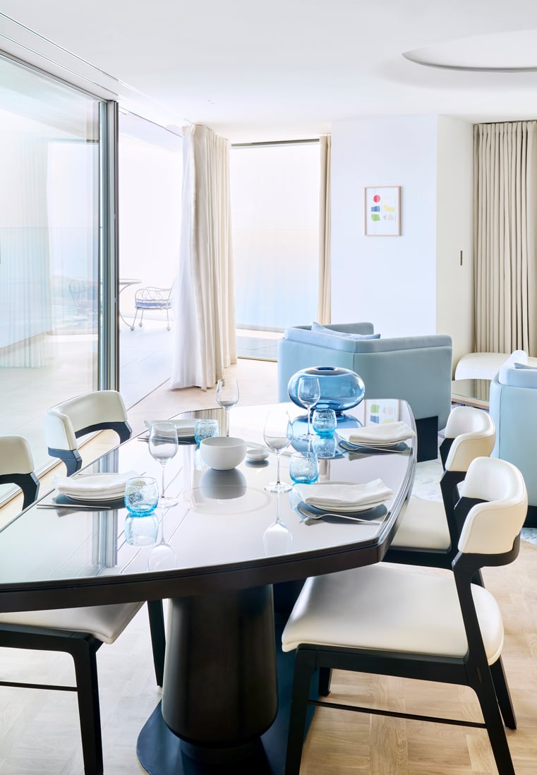 Long black table with plates and glasses with black and white chairs at the suite heaven.