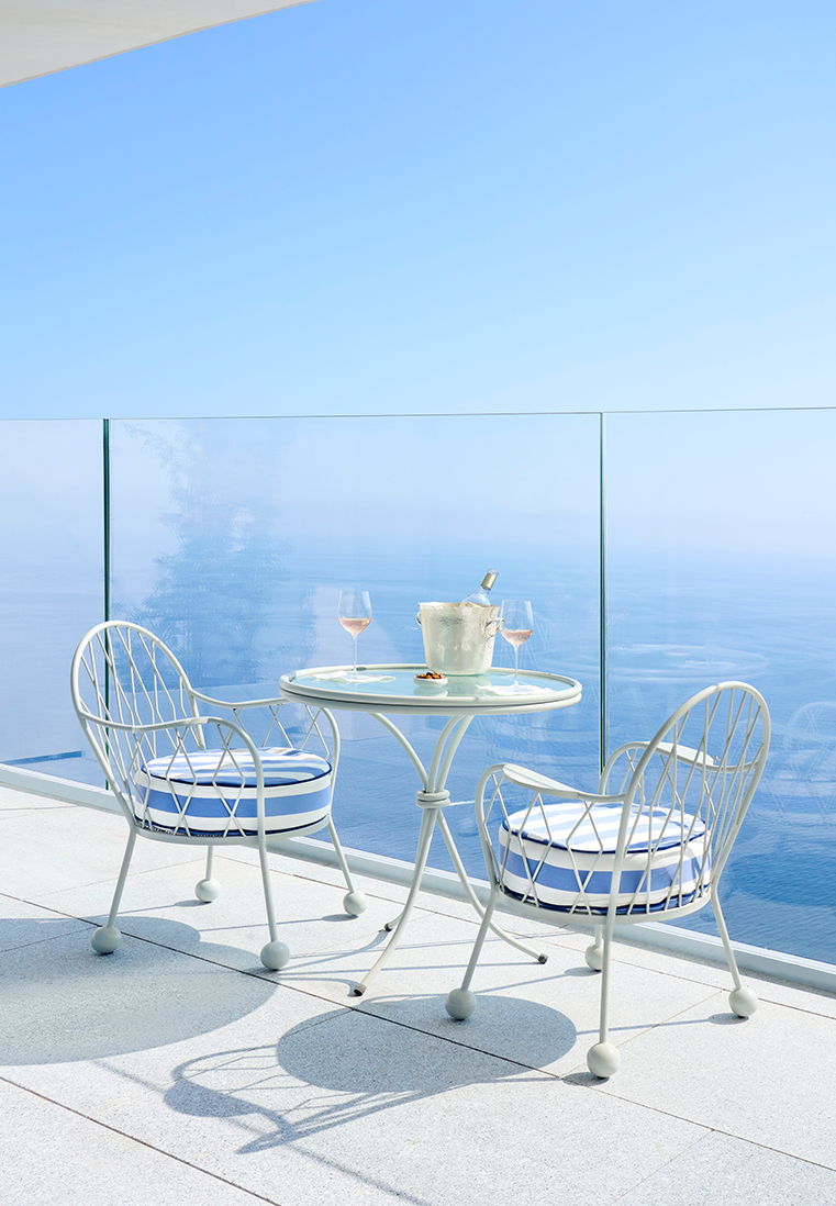 A table and two chairs with two wine glasses facing the sea.