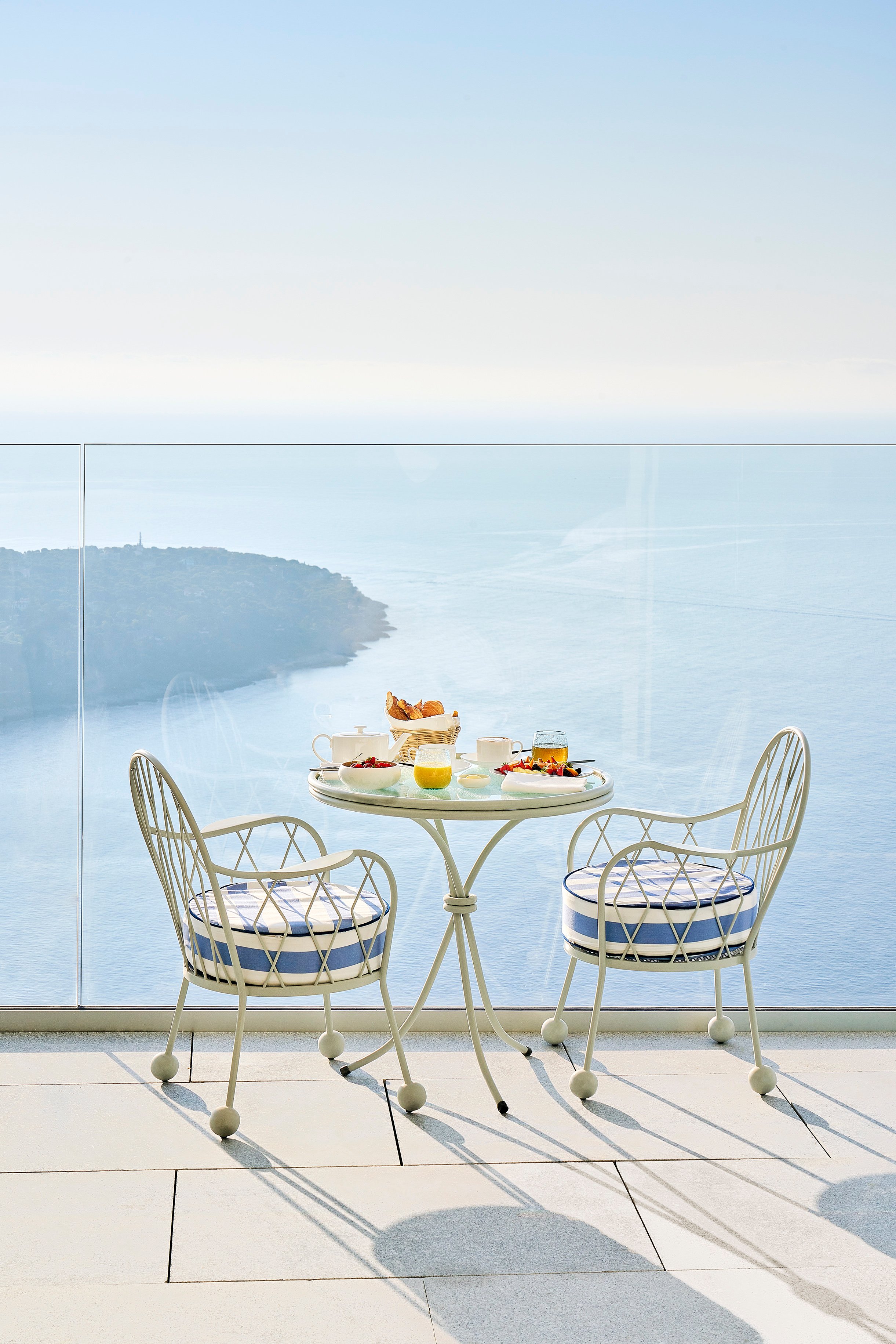 A table and two chairs with breakfast facing the sea.