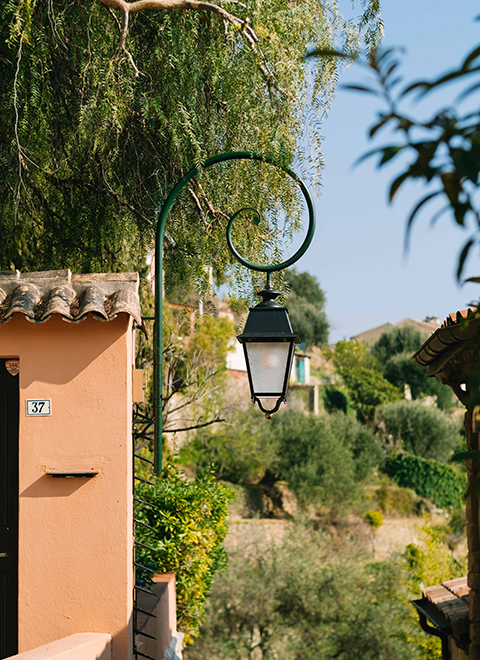 A street lamp on a house with a view of a village in the background.
