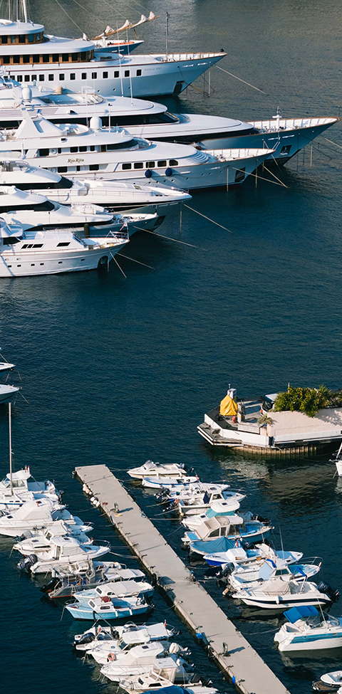 Vue de haut sur une partie du port de Monaco avec des bateaux, yachts et superyachts amarrés.