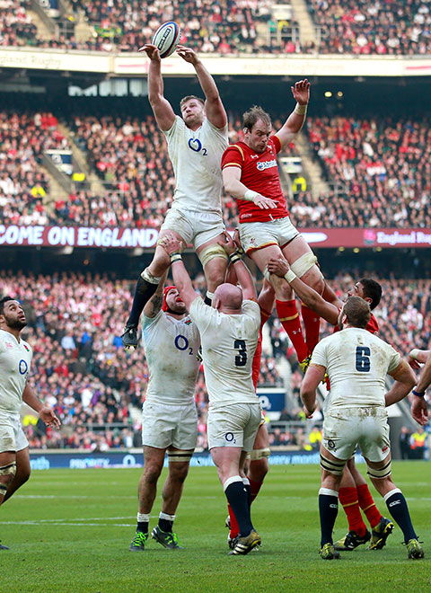 Two rugby players reaching for the ball in a rugby game