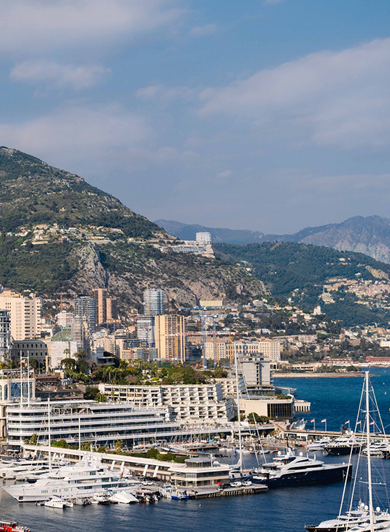 Vue du port de Monaco avec des bateaux, yachts et superyachts et le Maybourne Riviera sur la falaise.