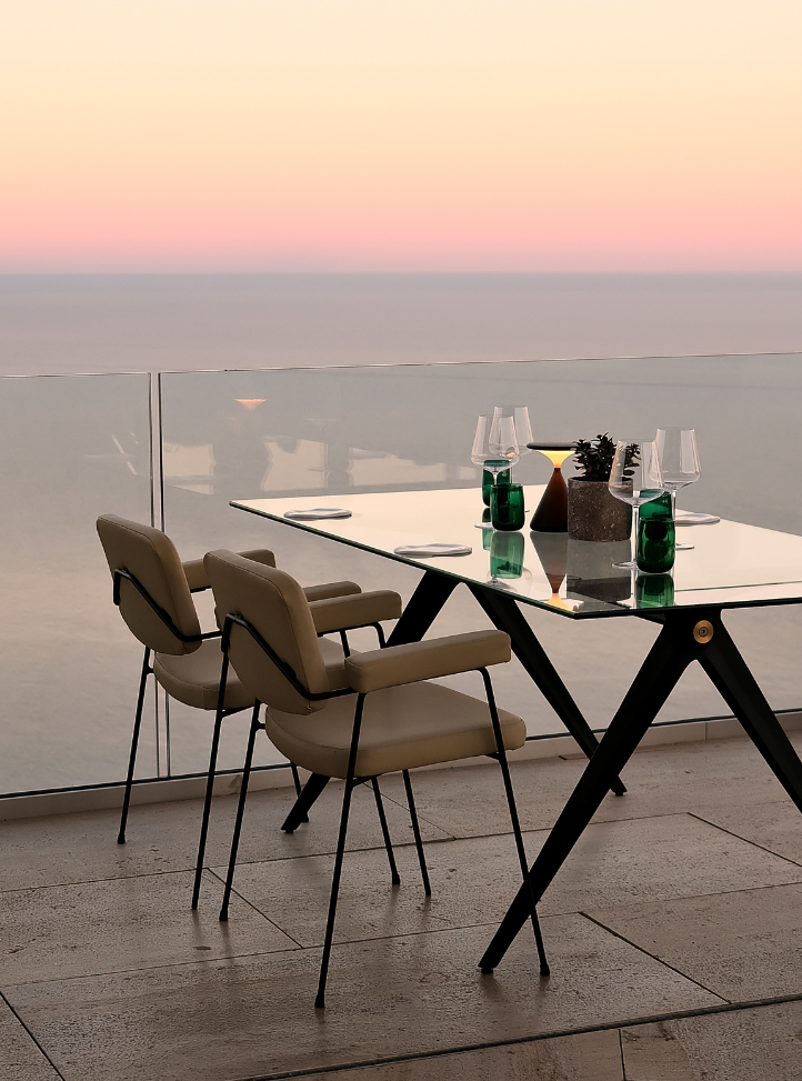 Table de restaurant en extérieur face à la mer au couché du soleil - Restaurant table at sunset over looking the sea from the terrace