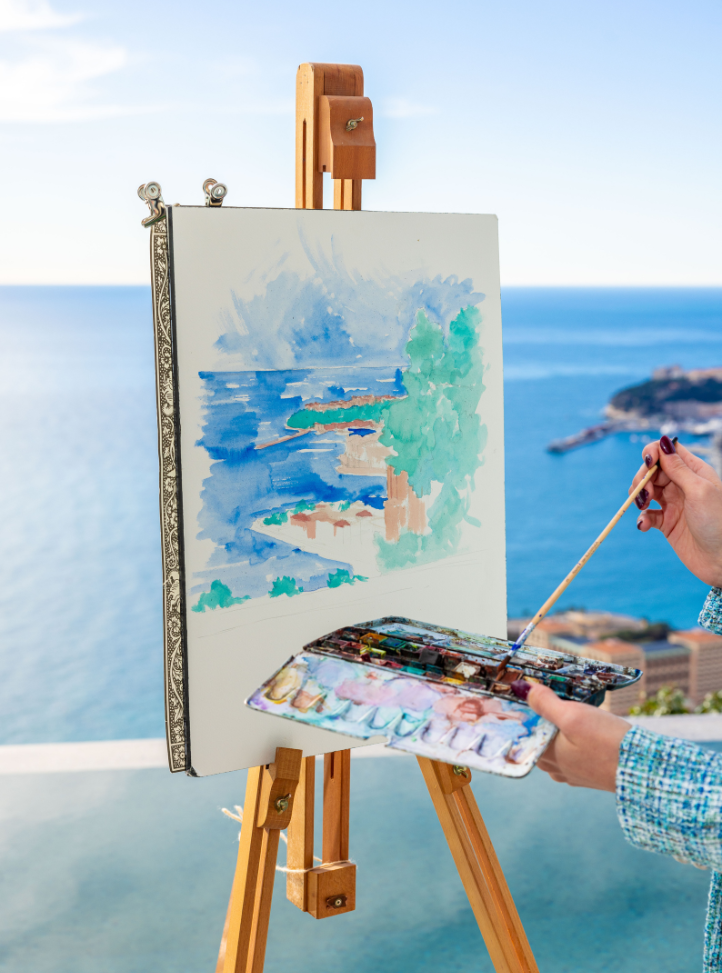 mains qui tiennent une palette de peinture devant un tableau face à la mer - hands holding a painting palette in front of a canva in front of the sea