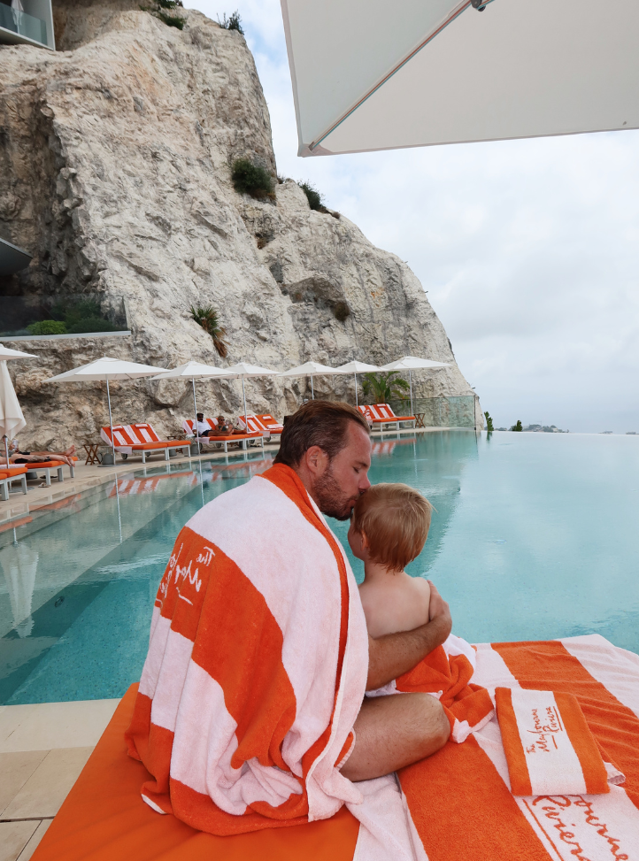 un homme tenant son fils dans ses bras face sur un transat devant une piscine - a man holding his son, in his arm on a sun lounger in front of a pool