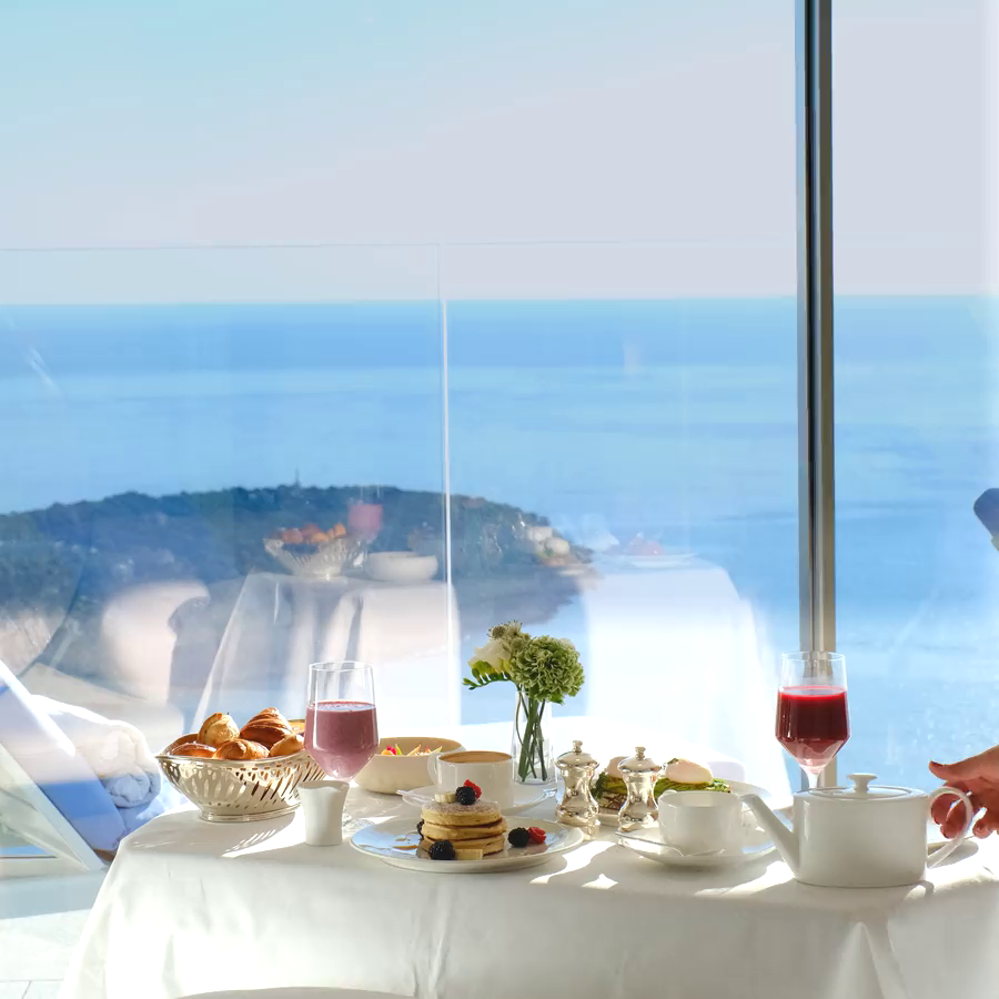 A table with a white tablecloth with food and a sea view.