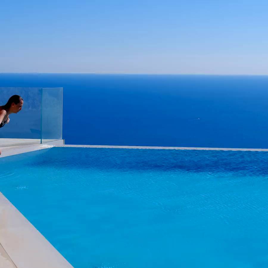 A person jumping into the infinity pool with the sea in the background.