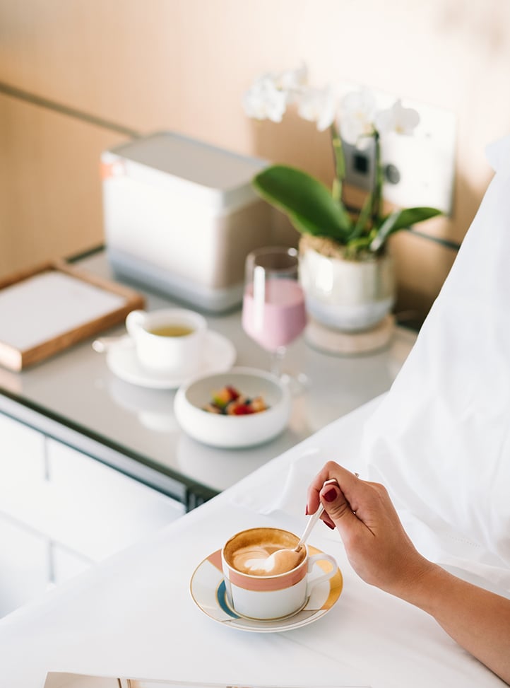 A hand stirring a coffee in bed at The Maybourne Riviera
