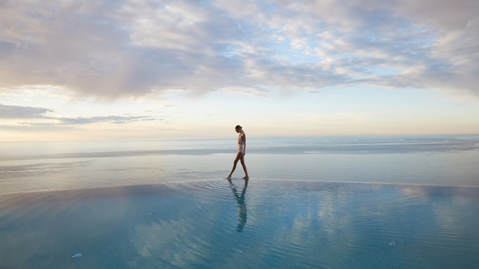 A model standing at the edge of the pool at The Maybourne Riviera