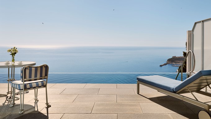 Terrace with striped seating and loungers overlooking the sea and harbour.